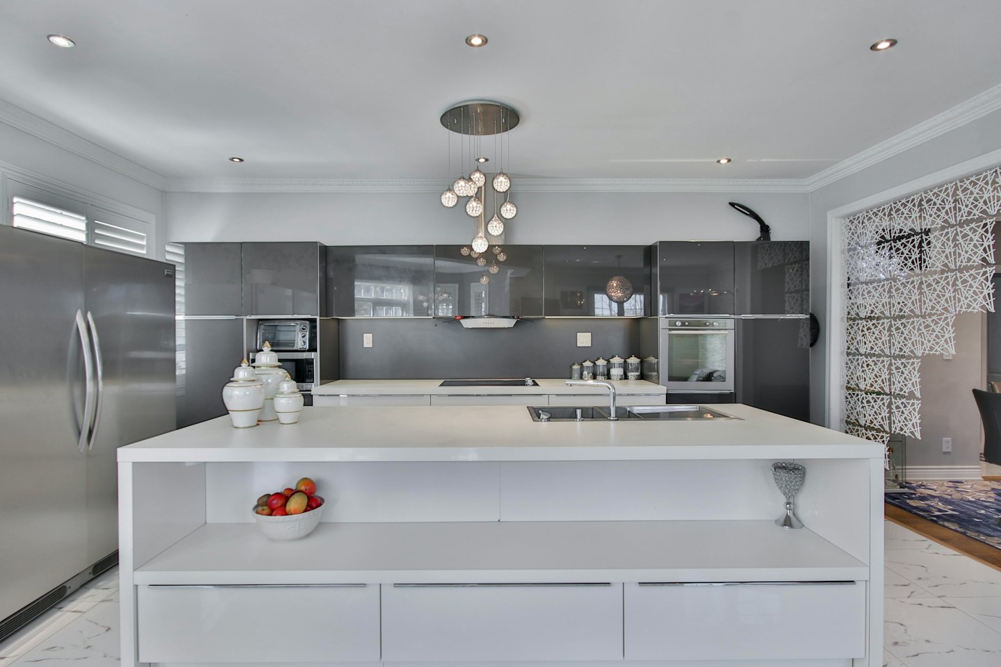 Modern luxury kitchen with a large white island and grey cabinets.